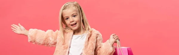 Plano panorámico de niño sonriente y lindo sosteniendo bolsa aislada en rosa - foto de stock