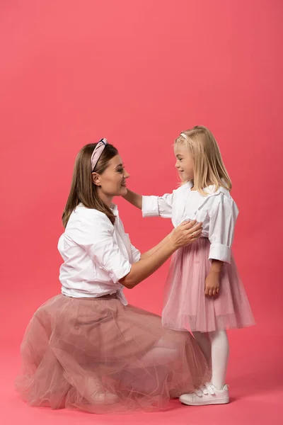 Side view of smiling daughter and mother hugging on pink background — Stock Photo
