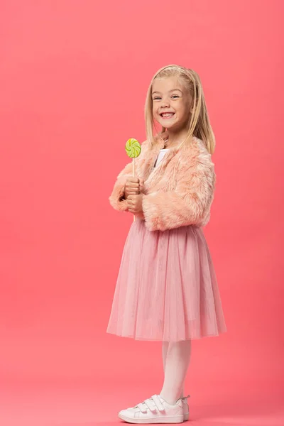 Smiling and cute kid holding lollipop on pink background — Stock Photo