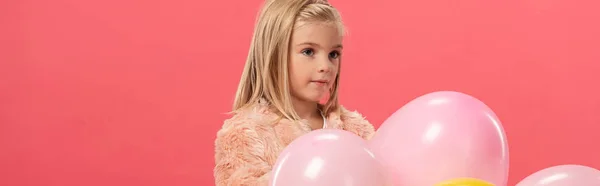 Panoramic shot of cute and stylish kid holding balloons isolated on pink — Stock Photo