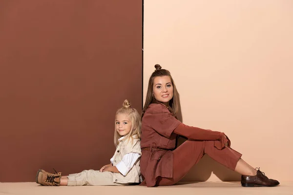 Sonriente hija y madre mirando a la cámara sobre fondo beige y marrón - foto de stock