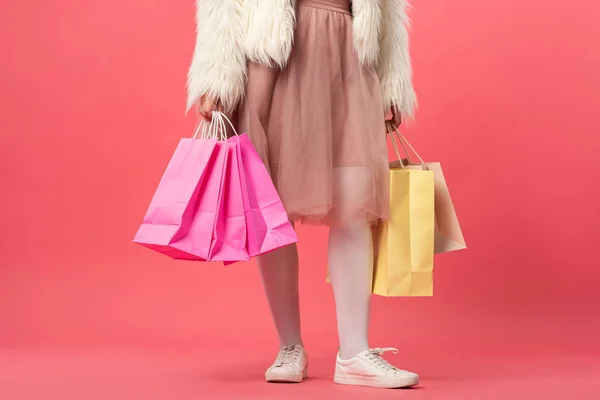 Vista cortada de mulher segurando sacos de compras no fundo rosa — Fotografia de Stock