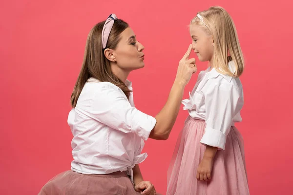 Vista laterale della madre toccare il naso di sua figlia isolato su rosa — Foto stock