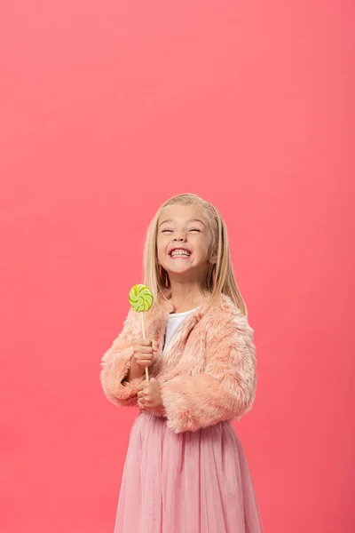 Smiling and cute kid holding lollipop isolated on pink — Stock Photo