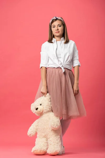 Attraktive Frau mit Teddybär und Blick in die Kamera auf rosa Hintergrund — Stockfoto