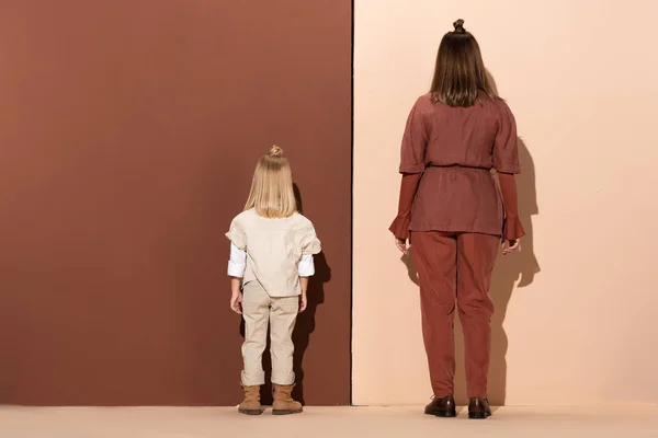 Вид сзади стильной дочери и матери на бежевом и коричневом фоне — стоковое фото