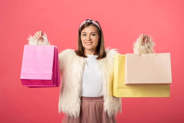 Donna attraente e sorridente che tiene borse della spesa isolate sul rosa — Foto stock