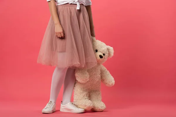 Обрізаний вид жінки, що тримає плюшевого ведмедя на рожевому фоні — стокове фото