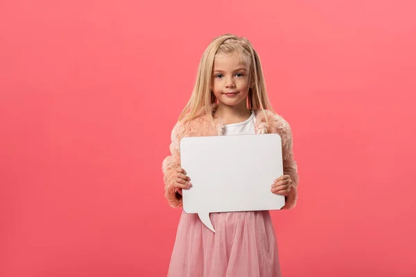 Lindo y sonriente niño sosteniendo vacío discurso burbuja aislado en rosa - foto de stock