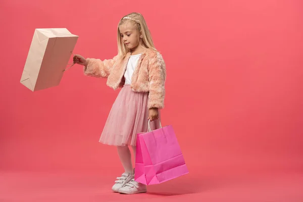 Garoto bonito segurando sacos de compras no fundo rosa com espaço de cópia — Fotografia de Stock