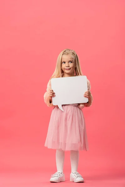 Lindo y sonriente niño sosteniendo el habla vacía burbuja sobre fondo rosa - foto de stock