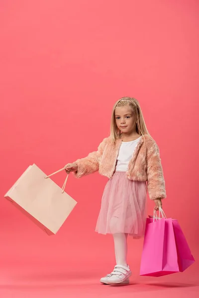 Garoto bonito segurando sacos de compras no fundo rosa com espaço de cópia — Fotografia de Stock