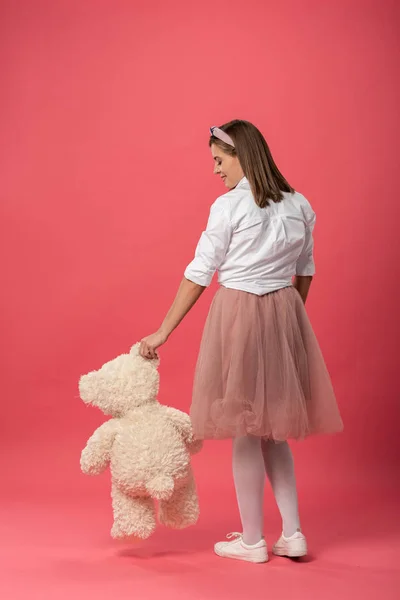 Back view of woman holding teddy bear on pink background — Stock Photo