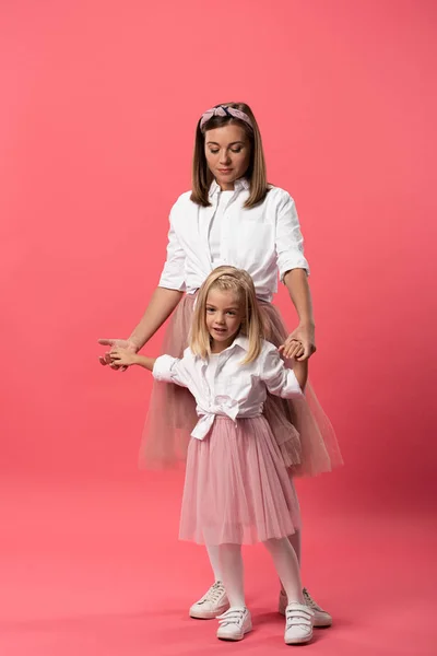 Sorrindo filha e mãe de mãos dadas em fundo rosa — Fotografia de Stock