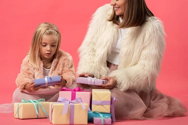 Cropped view of mother and daughter holding gifts on pink background — Stock Photo