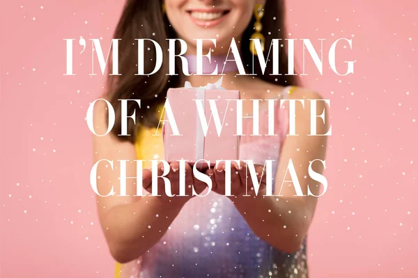 Cropped view of happy young stylish disco girl holding gift box on pink with i am dreaming of a white Christmas illustration — Stock Photo