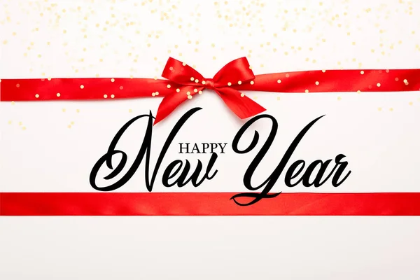 Top view of red ribbon and bow with happy new year lettering on white — Stock Photo