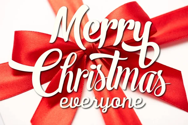 Primer plano de cinta de satén con lazo rojo decorativo con feliz Navidad todo el mundo letras en blanco - foto de stock