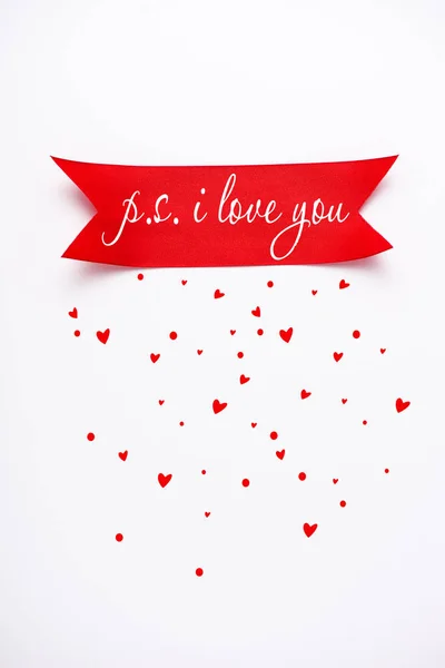 Top view of red satin ribbon with p.s. i love you letters near falling hearts on white — Stock Photo