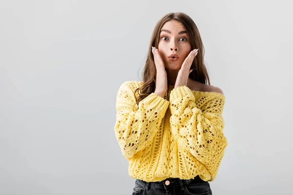 Shocked girl looking at camera while holding hands near face isolated on grey — Stock Photo