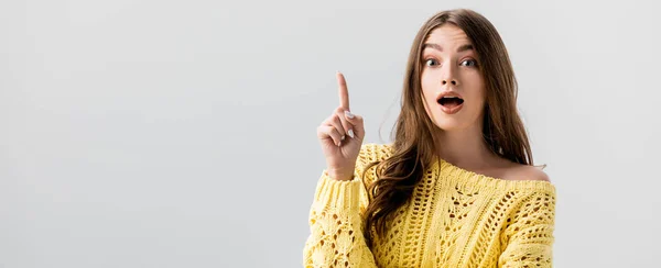 Panoramic shot of surprised girl pointing with finger while looking at camera isolated on grey — Stock Photo