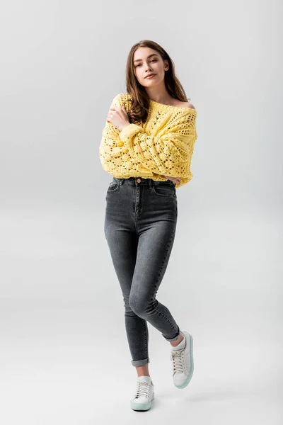 Full length view of confident young woman looking up while hugging herself isolated on grey — Stock Photo