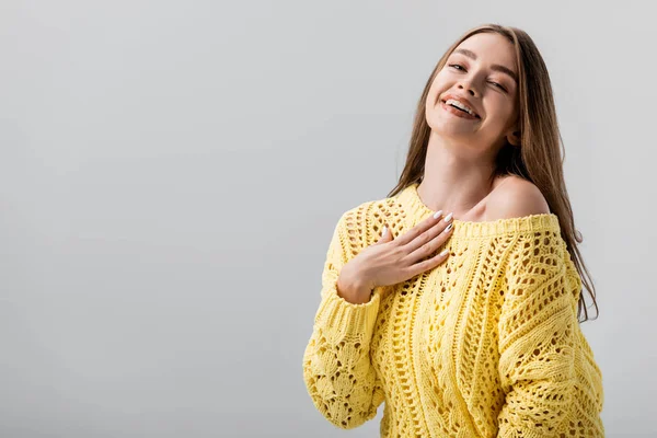 Beautiful girl laughing at camera while holding hand on chest isolated on grey — Stock Photo