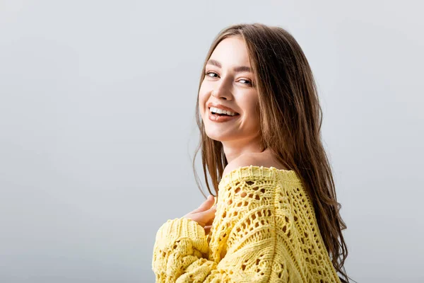 Cheerful girl looking at camera while holding hand on chest isolated on grey — Stock Photo