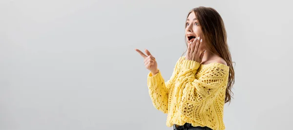 Panoramic shot of shocked girl pointing with finger and touching face isolated on grey — Stock Photo