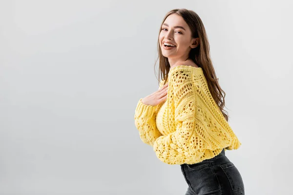 Alegre chica riendo en cámara mientras sosteniendo mano cerca pecho aislado en gris - foto de stock