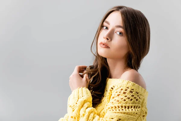 Beautiful, dreamy girl touching hair and looking at camera isolated on grey — Stock Photo