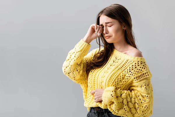 Unhappy girl in yellow sweater crying and wiping tears with hand isolated on grey — Stock Photo