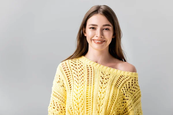 Приваблива дівчина в жовтому светрі, посміхаючись на камеру ізольована на сірому — стокове фото
