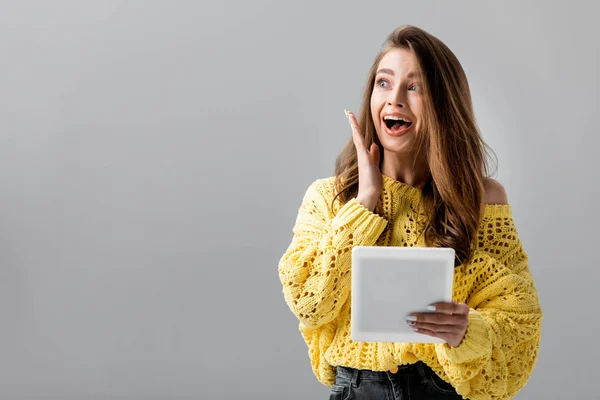 Shocked girl holding digital tablet and looking away isolated on grey — Stock Photo
