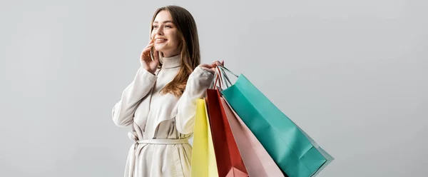 Panoramic shot of stylish girl looking away while holding shopping bags isolated on grey — Stock Photo