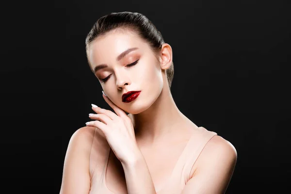 Beautiful young woman with closed eyes touching face isolated on black — Stock Photo