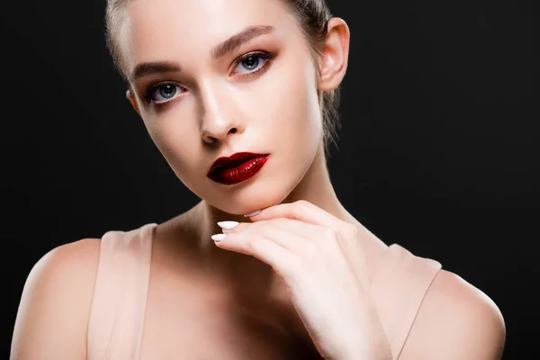 Atractiva joven con labios de color rojo brillante mirando a la cámara aislada en negro - foto de stock