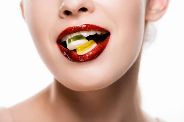 Cropped view of woman with red lips holding candies in mouth isolated on white — Stock Photo