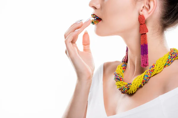 Partial view of girl in beaded necklace and earrings touching beads on lips isolated on white — Stock Photo