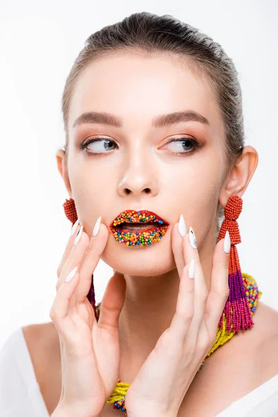 Beautiful girl in beaded necklace and earrings touching beads on lips isolated on white — Stock Photo