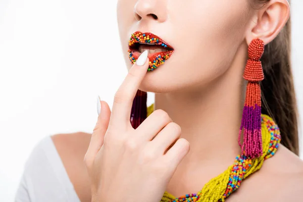 Partial view of girl in beaded necklace and earrings touching beads on lips isolated on white — Stock Photo