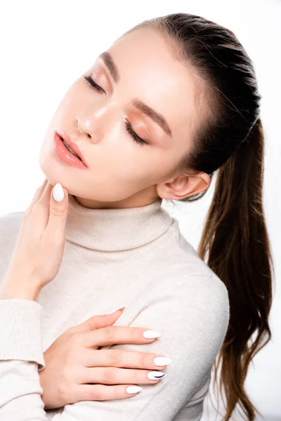Menina atraente com maquiagem natural tocando o rosto com os olhos fechados isolados no branco — Stock Photo