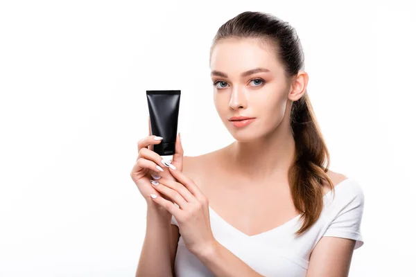 Beautiful girl looking at camera while holding tube with hand cream isolated on white — Stock Photo