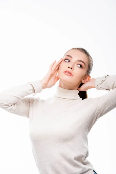 Schöne junge Frau mit natürlichem Make-up, die wegschaut, während sie Gesicht isoliert auf Weiß berührt — Stockfoto