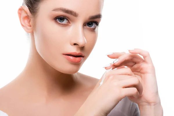 Beautiful young woman applying hand cream and looking at camera isolated on white — Stock Photo