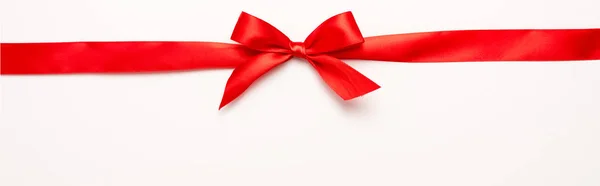 Panoramic shot of red ribbon with bow on white — Stock Photo