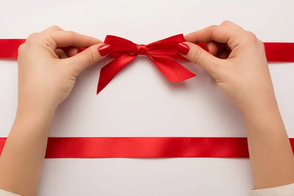 Cropped view of woman touching red bow on white — Stock Photo