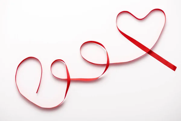 Top view of heart-shaped red ribbon on white — Stock Photo