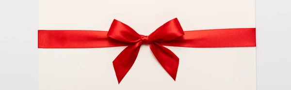 Panoramic shot of red satin bow on envelope isolated on white — Stock Photo