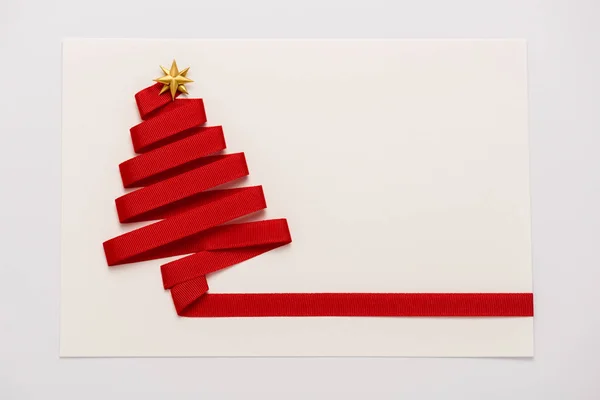 Вид зверху на червону стрічку з носом золотої зірки на паперовій конверті ізольовано на білому — стокове фото